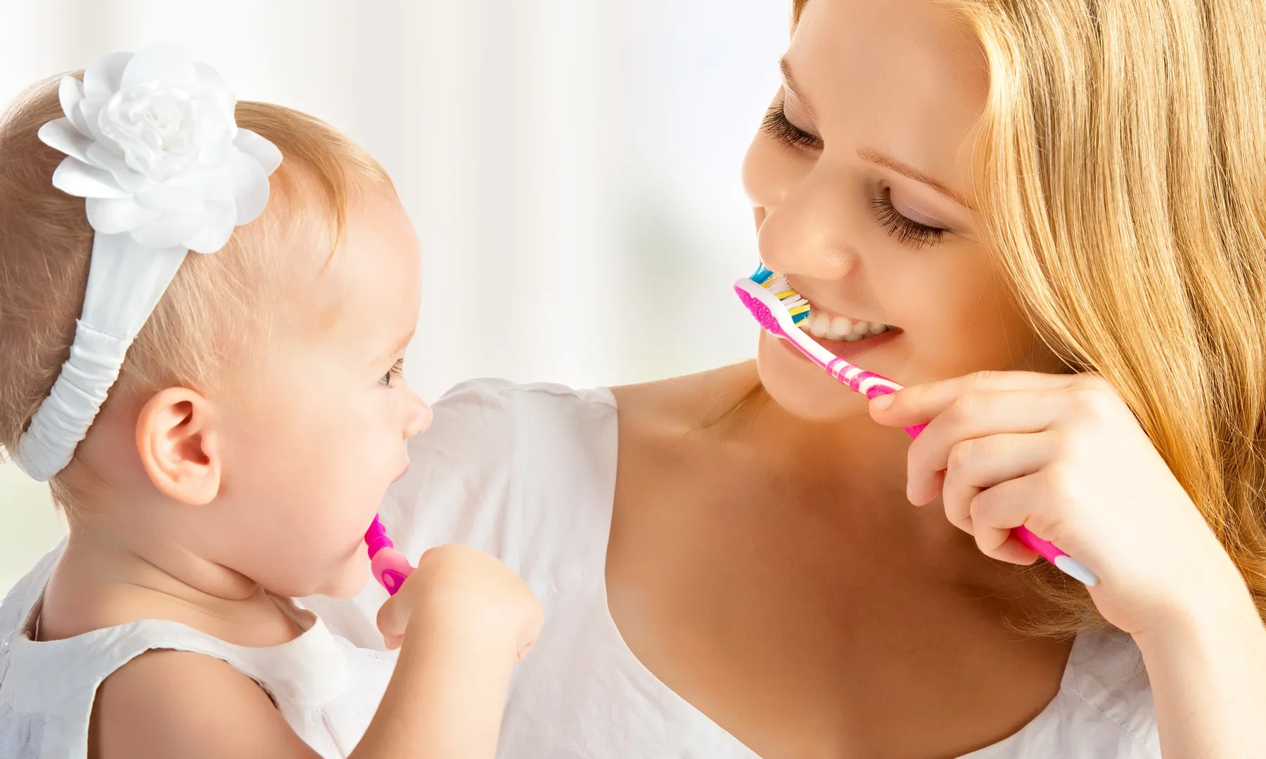 A mother and young child brushing their teeth together